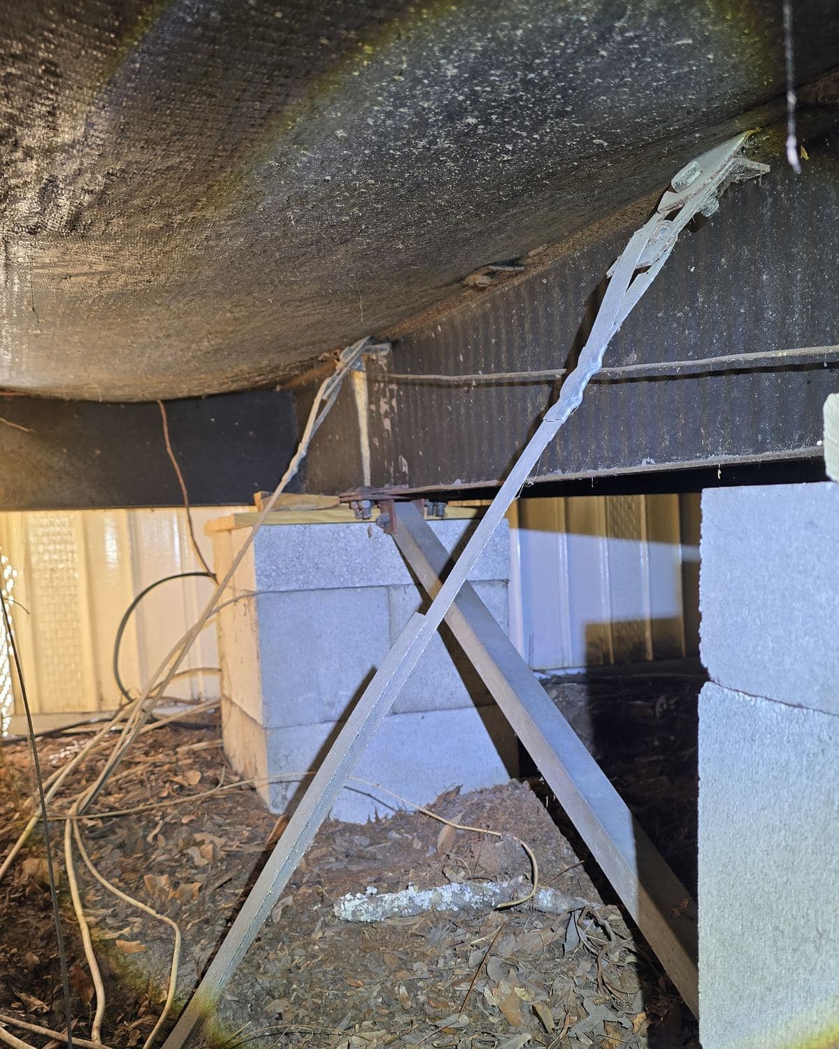 Masonry piers and steel tie-down straps under a manufactured home