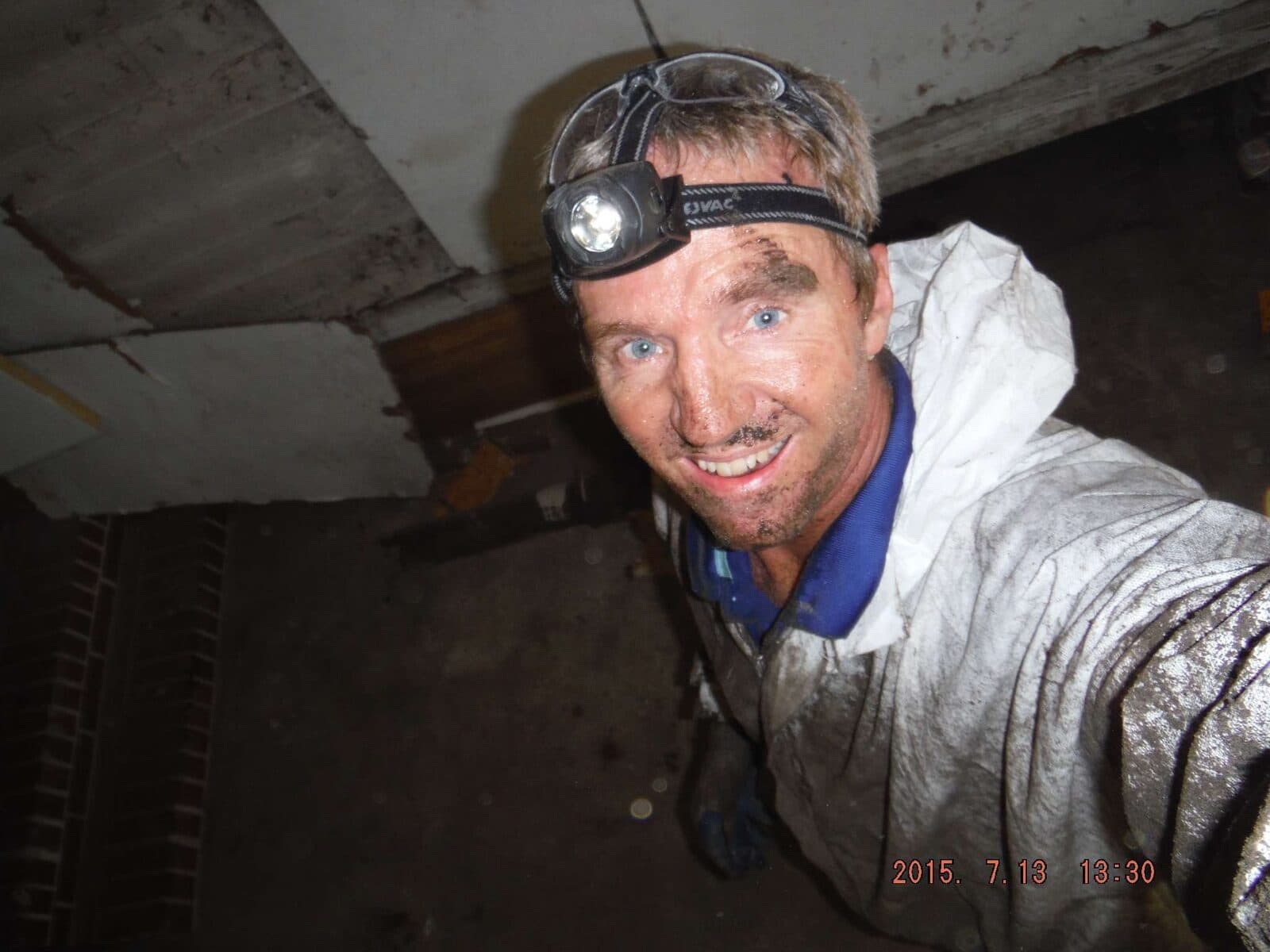 Paul Drayton inspecting a crawlspace in a protective suit